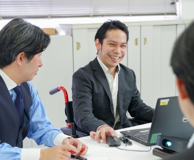 写真：笑顔で会議をする社員