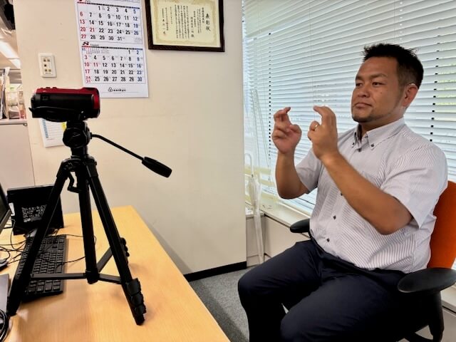 画像:聴覚障がい者の社員がビデオカメラに向かって自分の手話を撮影している様子